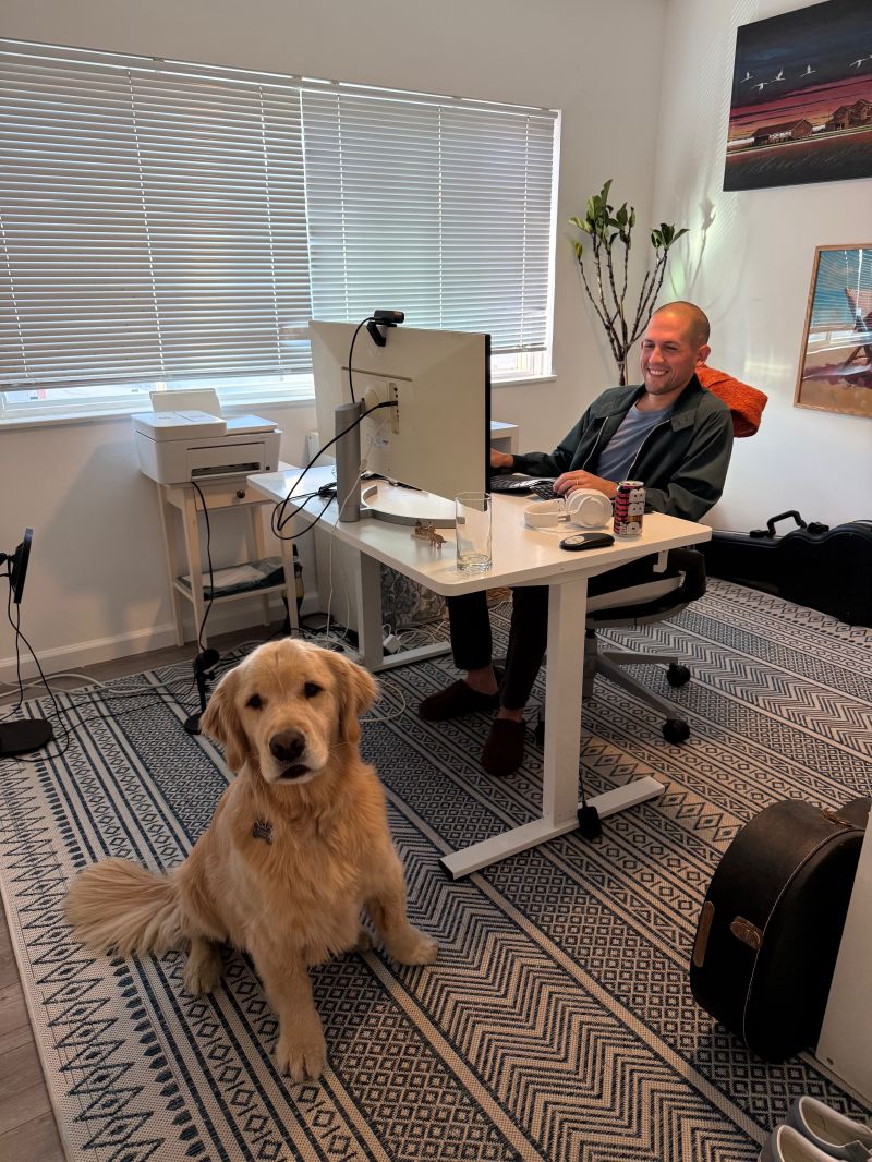 Aubrey at a desk with a golden retriever in a home office